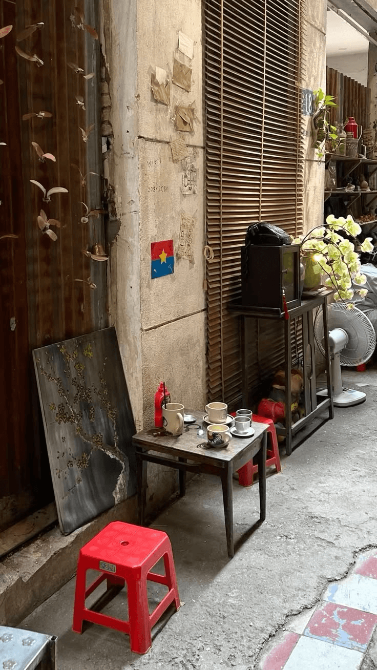 Coffee cups on a small table in an alley, a red stool beside it